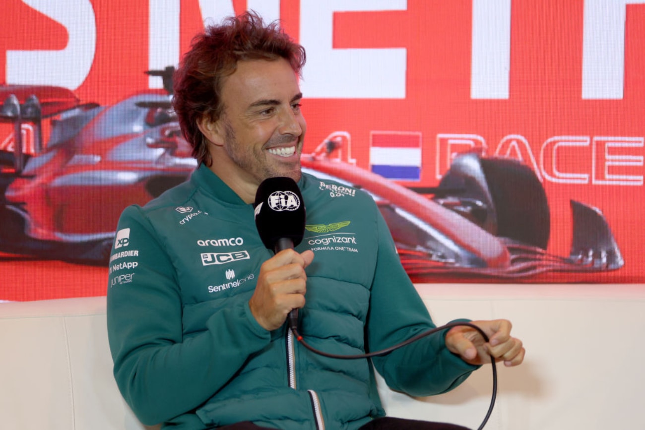 Fernando Alonso in a green jacket holding a microphone at the v2023 Dutch Grand Prix