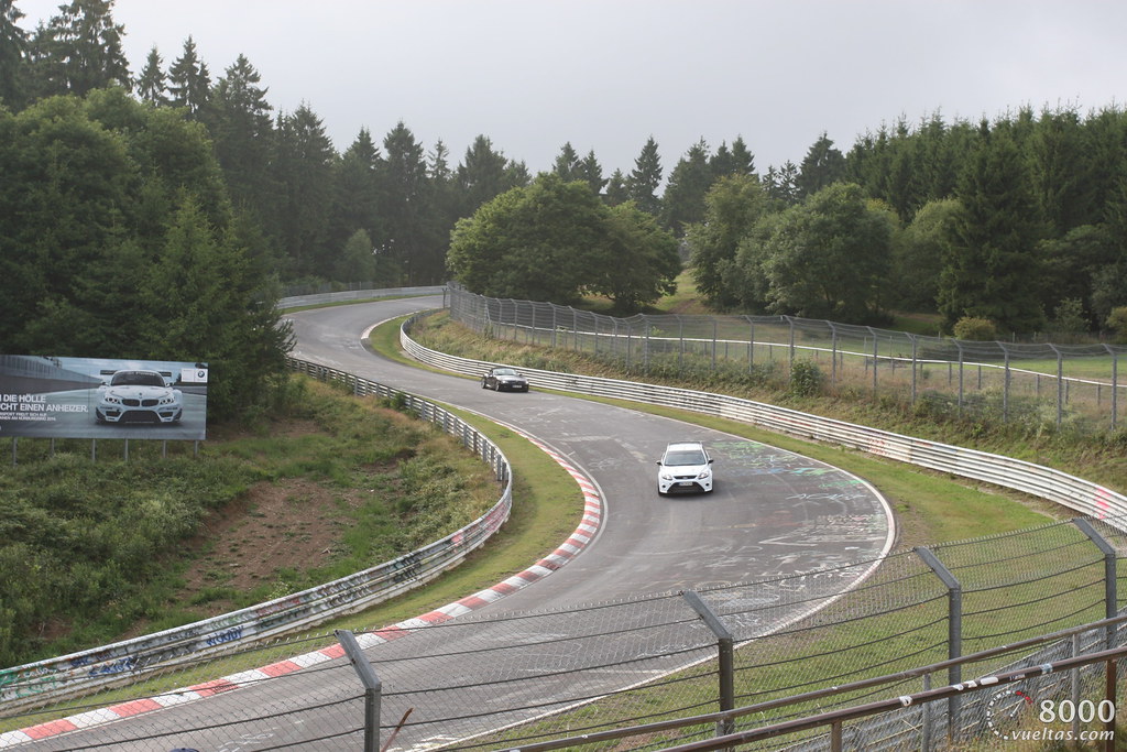 a car driving down a winding road near a forest