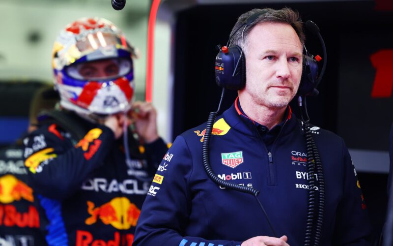 a man in a red bull racing suit with headphones on